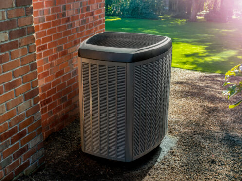 A heat pump along a brick wall in an alleyway